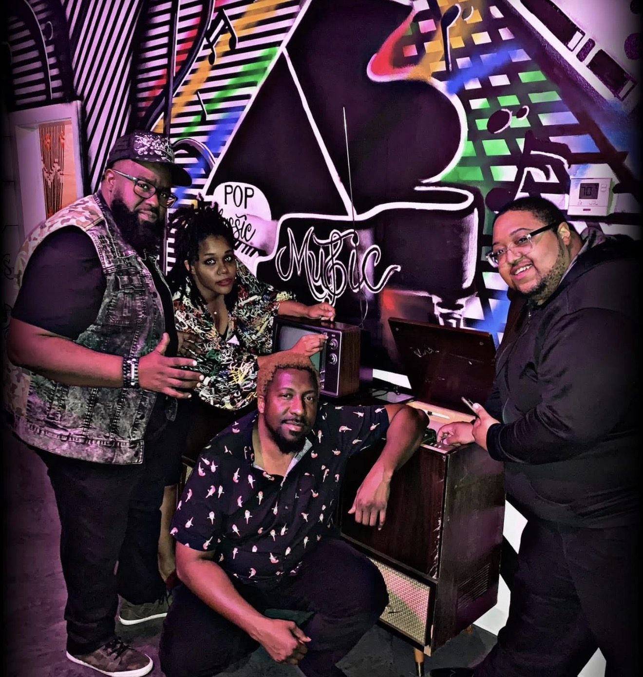 Band members in front of a colorful music mural